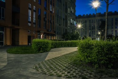 Night park paths and colored houses at summer night. Night paths, benches and lanterns in a beautiful residential complex. Night summer park with lanterns and benches. Kyiv. Ukraine