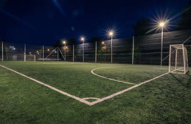 Soccer field with artificial green grass near the school. Amateur football field. Summer evening
