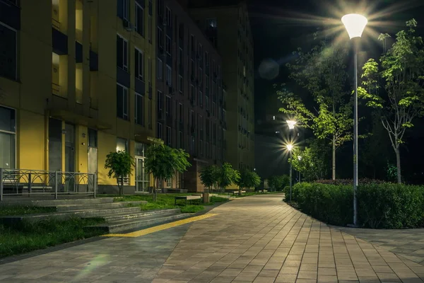 Night park paths and colored houses at summer night. Night paths, benches and lanterns in a beautiful residential complex. Night summer park with lanterns and benches. Kyiv. Ukraine