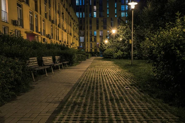 Night park paths and colored houses at summer night. Night paths, benches and lanterns in a beautiful residential complex. Night summer park with lanterns and benches. Kyiv. Ukraine