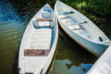 White pleasure boats at the pier on a small river in the city park. Summer day. A cluster of pleasure boats on a wooden pier. High quality photo
