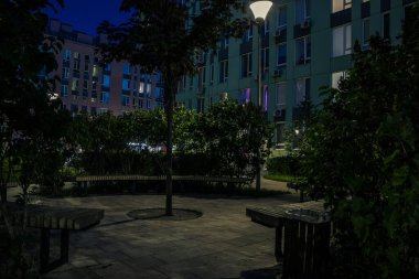 Night park paths and colored houses at summer night. Night paths, benches and lanterns in a beautiful residential complex. Night summer park with lanterns and benches. Kyiv. Ukraine