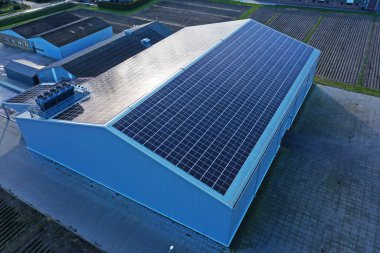 Güneş ışığıyla maviye boyanmış bir şirketin çatısındaki güneş panelleri. Güneş panelleri güneş ışığından enerji elde etmek için ucuz ve sürdürülebilir bir yoldur. Fotoğraf, uçan bir dronla çekildi.