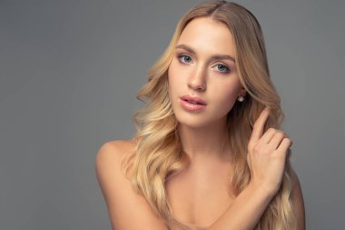 Gri arkaplanda uzun kıvırcık saçlı güzel bir sarışının portresi boynundaki küçük taşlarla süslenmiş.