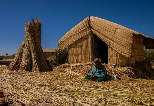 Mujer en la isla de Uros sentada frente a su casa y trabajando Imagen De Stock
