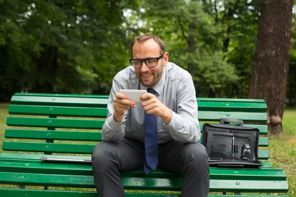 Podnikatel sedí na lavičce a chatování — Stock fotografie