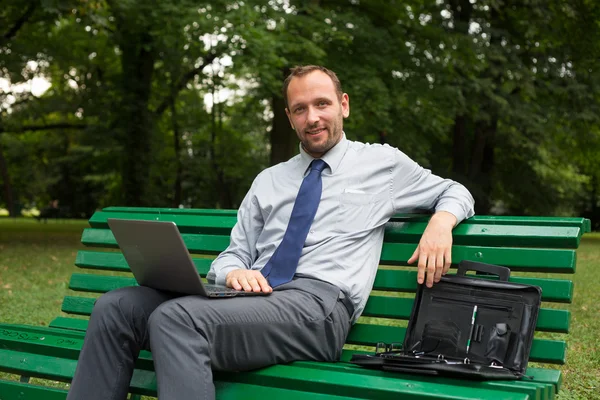 Empresario con portátil en el parque — Foto de Stock