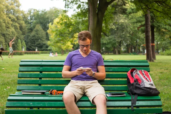 Студент с телефоном на скамейке — стоковое фото