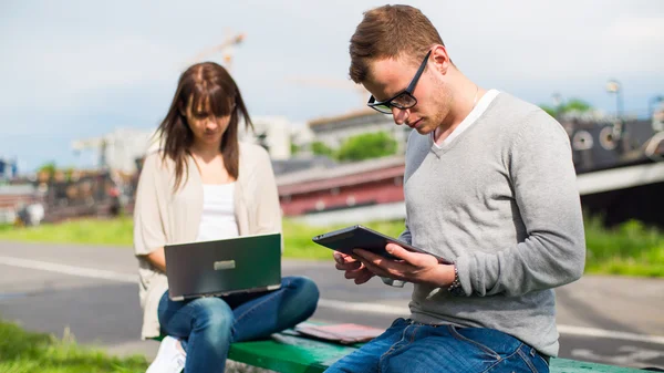 Studenti s tablety a notebooky v parku — Stock fotografie