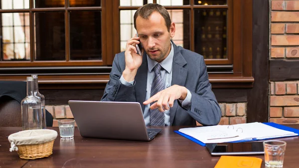 Homem de negócios com laptop e telefone celular — Fotografia de Stock