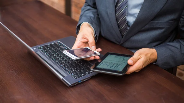 Biznesmen z laptopa, telefonu komórkowego i tabletki — Zdjęcie stockowe