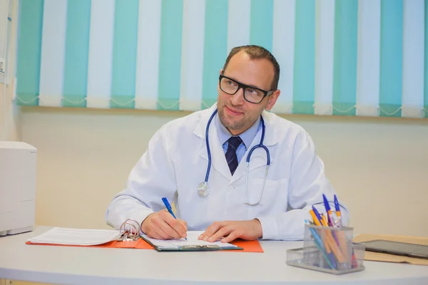 Doctor sitting behind desk — Stock Photo, Image