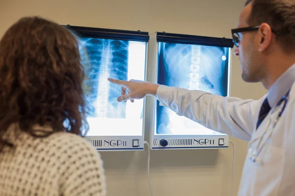 Arzt mit Patient schaut sich Röntgenbilder an — Stockfoto