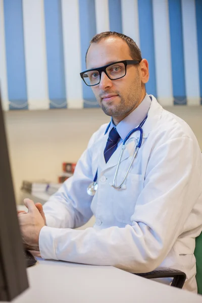 Läkare som sitter bakom skrivbord — Stockfoto