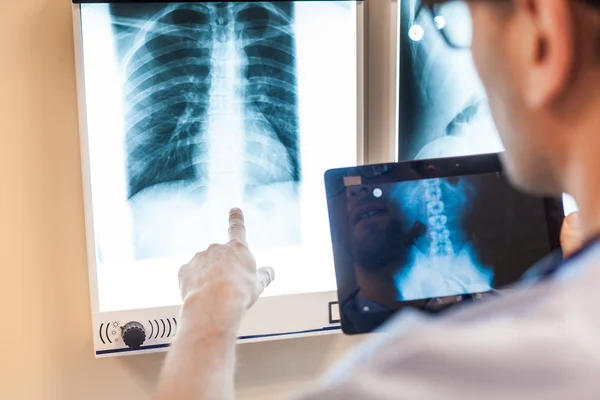 Doctor with tablet examing x-ray pictures — Stock Photo, Image