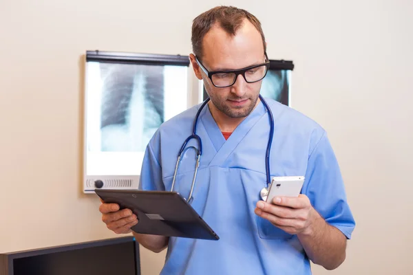 Medico con tablet e telefono cellulare — Foto Stock