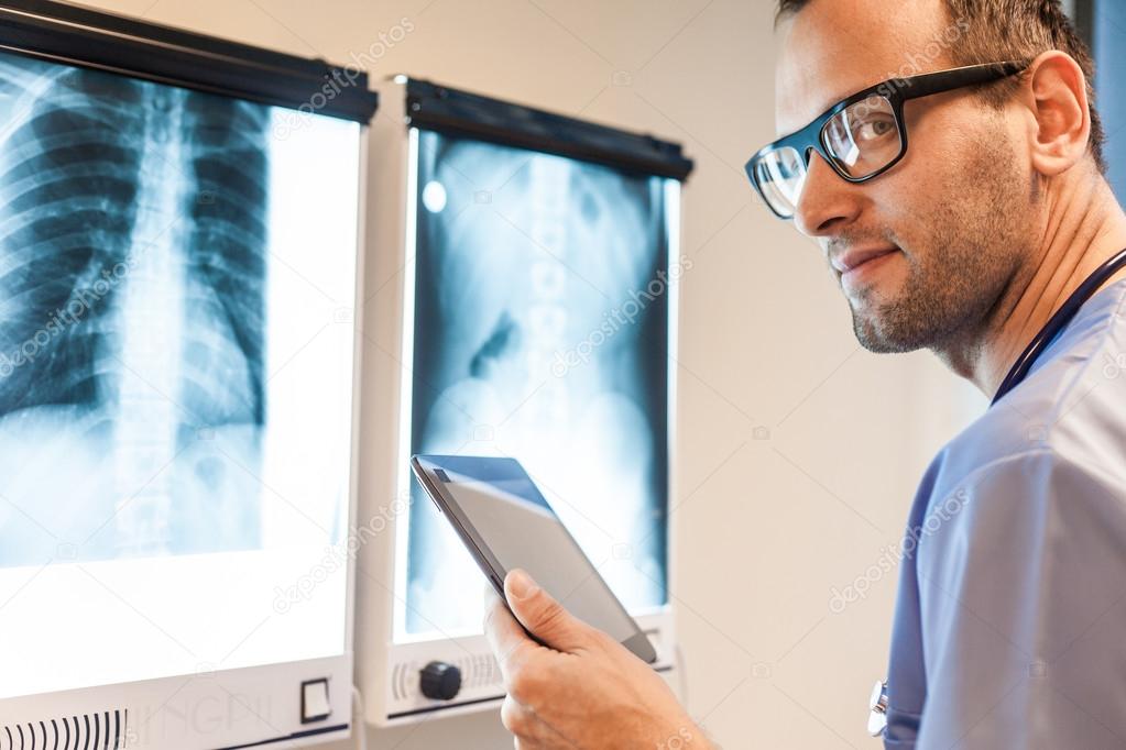 Doctor with tablet examing x-ray pictures