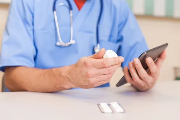 Doctor holding tablet and pills — Stock Photo, Image