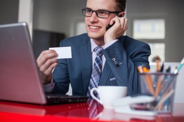 cep telefonu ve beyaz kartvizit tutan işadamı