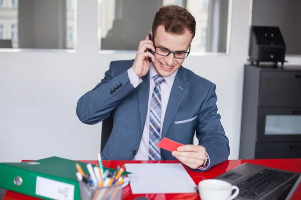 Empresário segurando telefone celular e cartão de visita — Fotografia de Stock