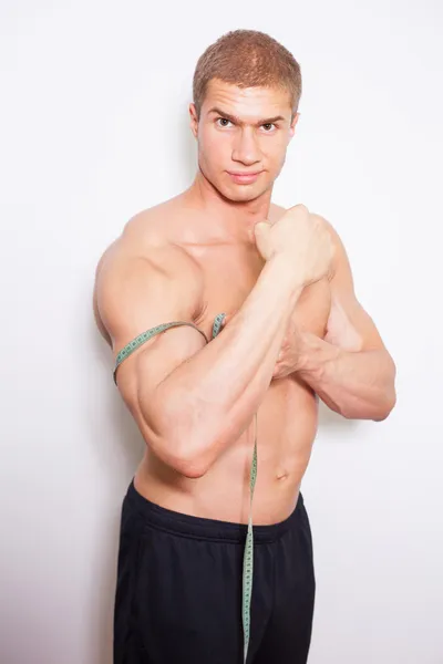 Bodybuilder mäter biceps — Stockfoto