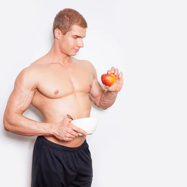 Bodybuilder with white bowl and apple — Stock Photo, Image