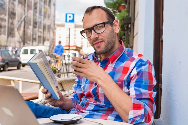 Человек читает книги и пьет кофе — стоковое фото