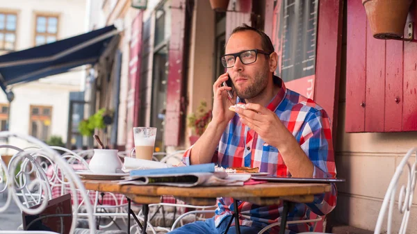 Homem comendo e usando celular — Fotografia de Stock