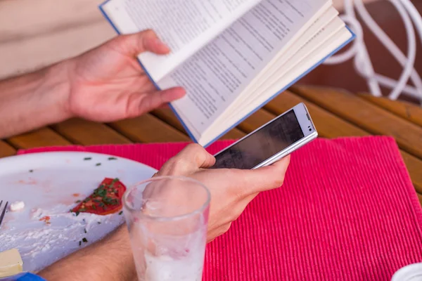 Male hands holding book and mobile phone — Stock Photo, Image