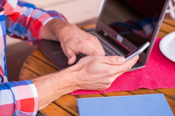 Człowiek za pomocą laptopa i telefon komórkowy — Zdjęcie stockowe