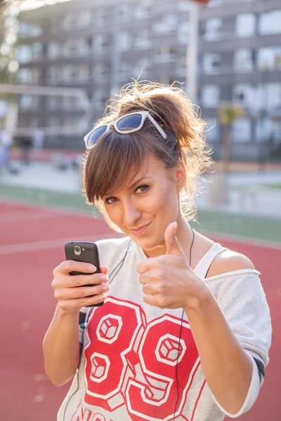 Chica sosteniendo el teléfono y mostrando el pulgar hacia arriba — Foto de Stock