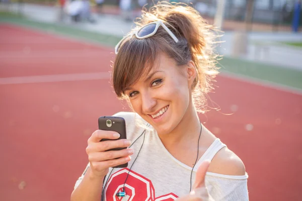 Dívka drží telefon a zobrazeno palec — Stock fotografie