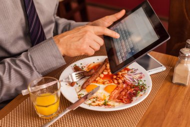 yemek yerken tablet kullanarak iş adamı