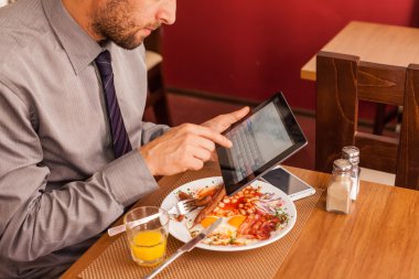 yemek yerken tablet kullanarak iş adamı