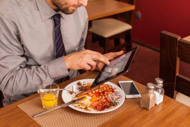 yemek yerken tablet kullanarak iş adamı