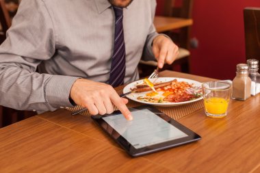 yemek yerken tablet kullanarak iş adamı