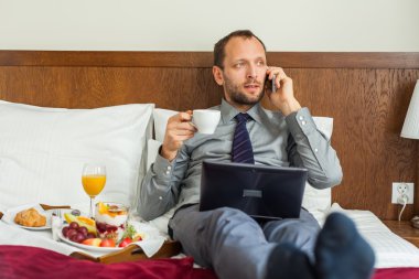 Kahvaltı sırasında telefon ve dizüstü kullanarak iş adamı