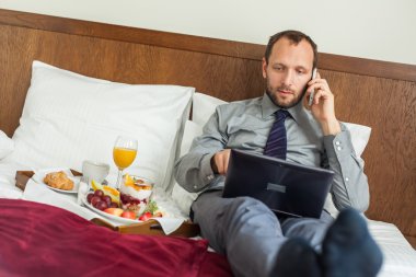 Kahvaltı sırasında telefon ve dizüstü kullanarak iş adamı
