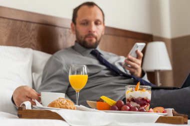 Kahvaltı sırasında telefon kullanarak iş adamı