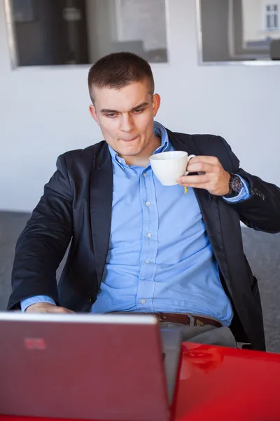 Zakenman met behulp van laptop en houden van koffie — Stockfoto