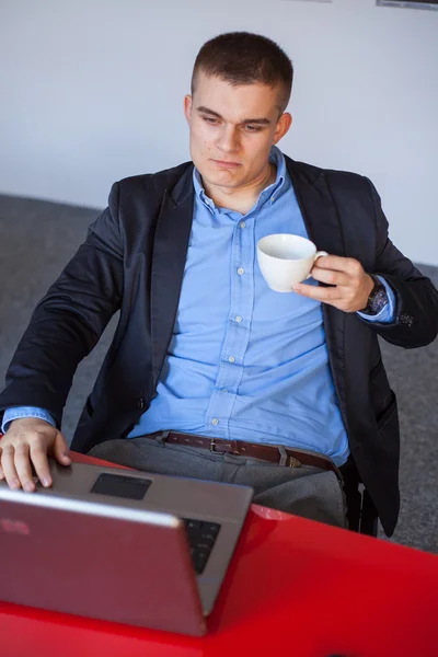 Empresario usando laptop y sosteniendo café —  Fotos de Stock