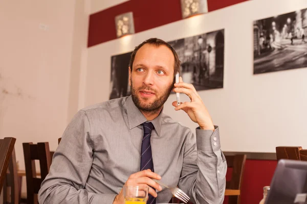 Businessman using phone while eating — Stock Photo, Image