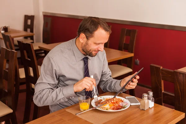 Affärsman med Tablet PC medan man äter — Stockfoto