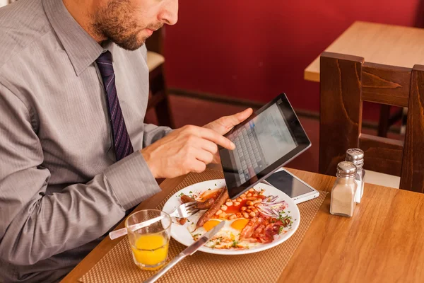 Бізнесмен використовує планшет під час їжі — стокове фото