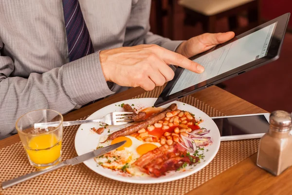 Empresário usando tablet enquanto come — Fotografia de Stock