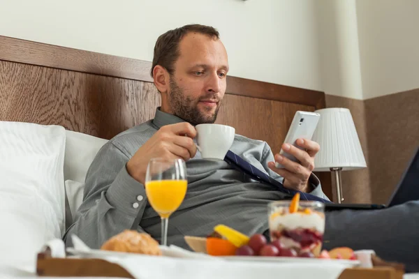 Affärsman med telefonen under frukosten — Stockfoto