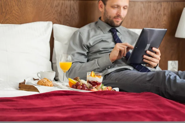 Kahvaltı sırasında tablet kullanarak iş adamı