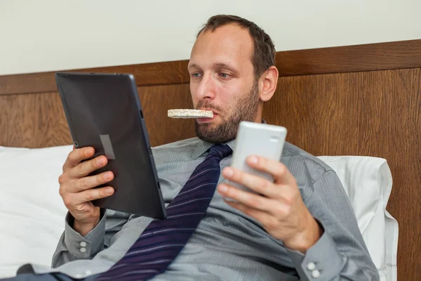 Businessman using phone and tablet during breakfast — Stock Photo, Image