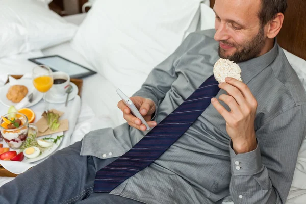 Businessman using phone during breakfast — Stock Photo, Image