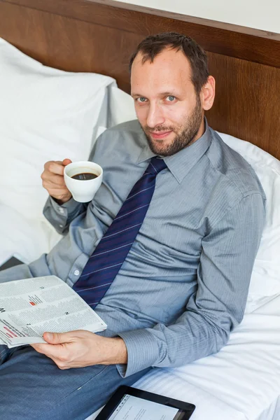 Businessman drinking coffee and reading newspaper — Stock Photo, Image